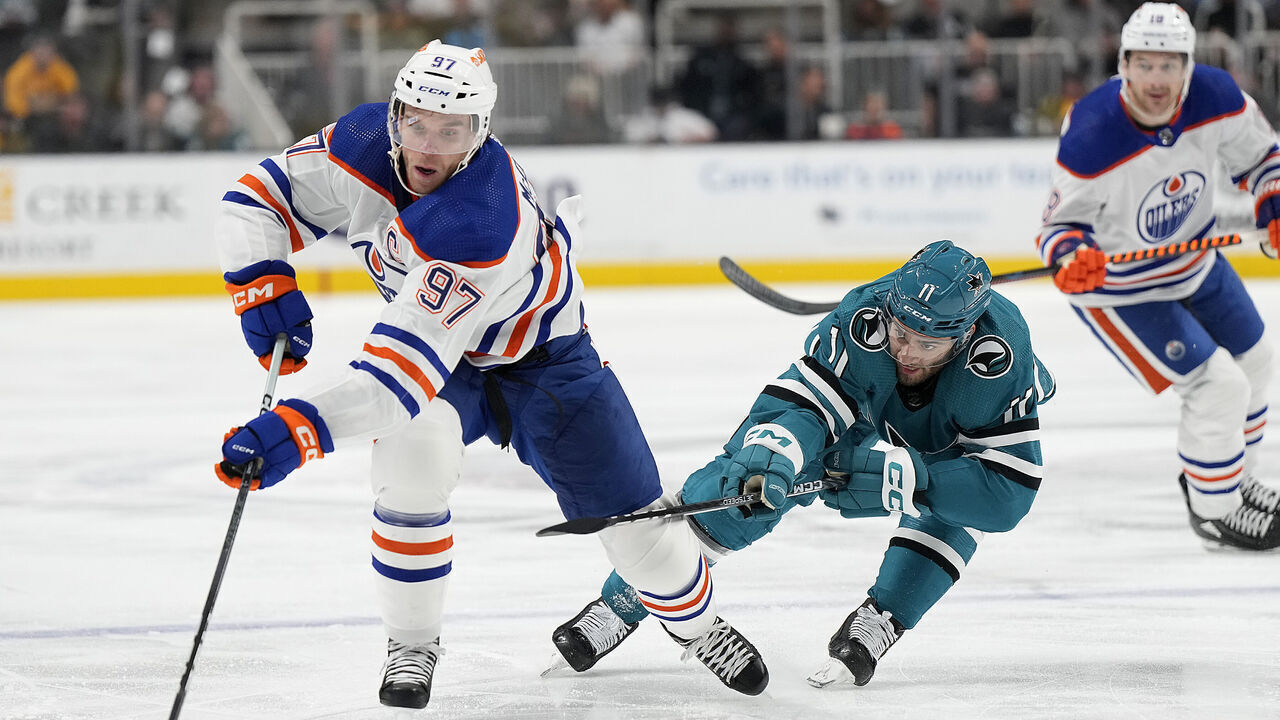 SAN JOSE, CALIFORNIA - NOVEMBER 09: Connor McDavid #97 of the Edmonton Oilers skates with the puck pursued by Luke Kunin #11 of the San Jose Sharks during the first period at SAP Center on November 09, 2023 in San Jose, California.