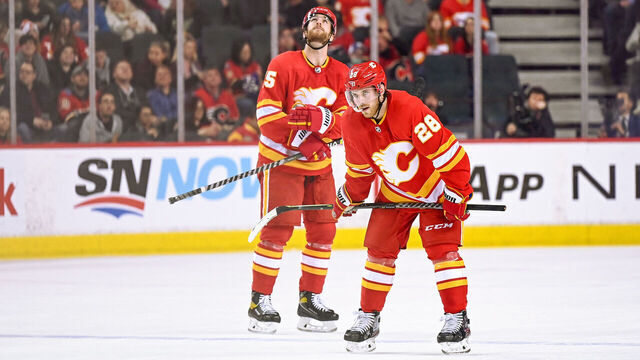 CALGARY, AB - MARCH 10: Calgary Flames Center Elias Lindholm (28) and Calgary Flames Defenceman Noah Hanifin (55) await a face-off during the second period of an NHL game where the Calgary Flames hosted the Tampa Bay Lightning on March 10, 2022, at the Scotiabank Saddledome in Calgary, AB.