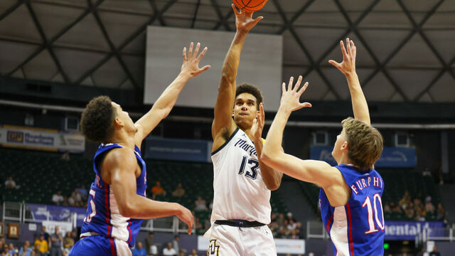 HONOLULU, HAWAII - NOVEMBER 21: Oso Ighodaro #13 of the Marquette Golden Eagles shoots between Kevin McCullar Jr. #15 and Johnny Furphy #10 of the Kansas Jayhawks during the first half of their game in the Allstate Maui Invitational at SimpliFi Arena on November 21, 2023 in Honolulu, Hawaii.
