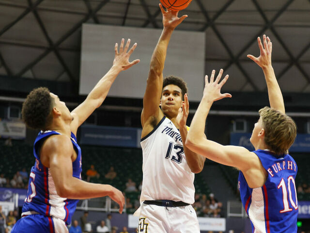 HONOLULU, HAWAII - NOVEMBER 21: Oso Ighodaro #13 of the Marquette Golden Eagles shoots between Kevin McCullar Jr. #15 and Johnny Furphy #10 of the Kansas Jayhawks during the first half of their game in the Allstate Maui Invitational at SimpliFi Arena on November 21, 2023 in Honolulu, Hawaii.