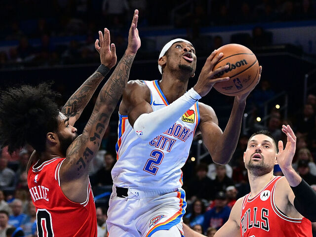 OKLAHOMA CITY, OKLAHOMA - NOVEMBER 22: Shai Gilgeous-Alexander #2 of the Oklahoma City Thunder goes to the basket between Coby White #0 and Nikola Vucevic #9 of the Chicago Bulls during the second half at Paycom Center on November 22, 2023 in Oklahoma City, Oklahoma.