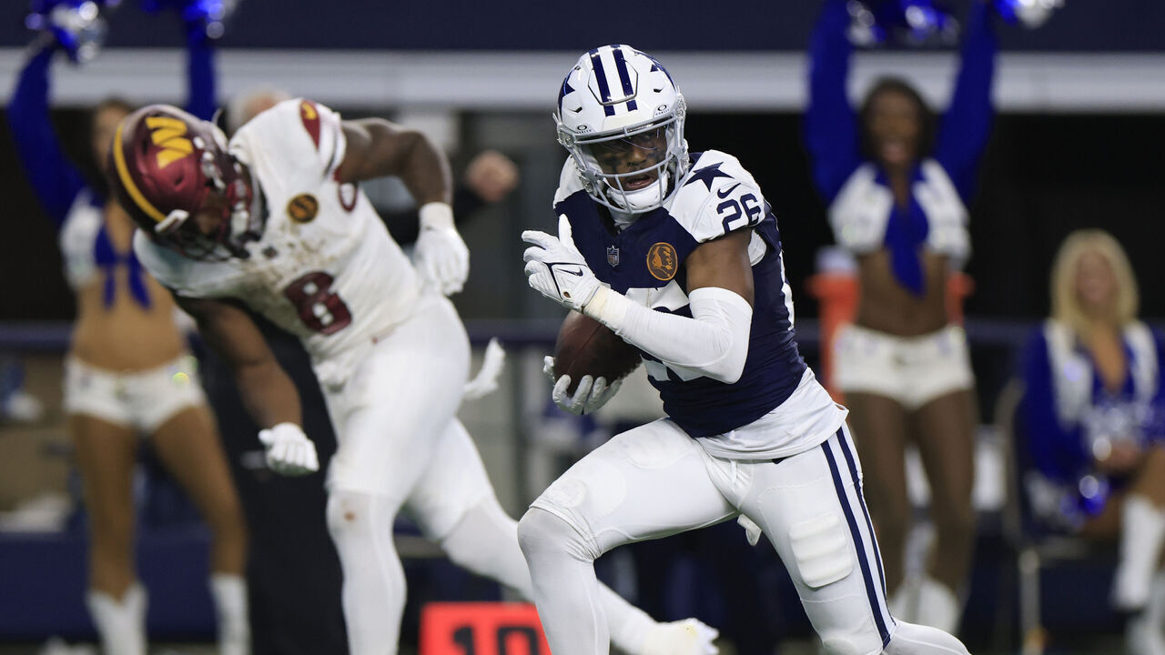 ARLINGTON, TEXAS - NOVEMBER 23: DaRon Bland #26 of the Dallas Cowboys returns an interception for a touchdown while chased by Brian Robinson Jr. #8 of the Washington Commanders during the fourth quarter at AT&T Stadium on November 23, 2023 in Arlington, Texas.