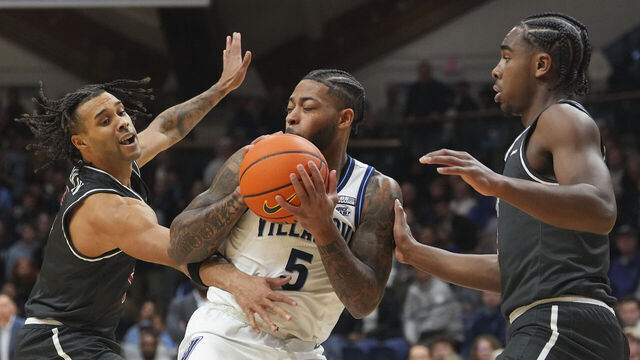 VILLANOVA, PENNSYLVANIA - NOVEMBER 29: Justin Moore #5 of the Villanova Wildcats controls the ball against Lynn Greer III #5 and Cameron Brown #3 of the Saint Joseph's Hawks in the first half at Finneran Pavilion on November 29, 2023 in Villanova, Pennsylvania.