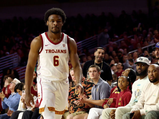 LOS ANGELES, CALIFORNIA - DECEMBER 10: LeBron James (2nd R) looks on from the stands towards Bronny James #6 of the USC Trojans during the first half against the Long Beach State 49ers at Galen Center on December 10, 2023 in Los Angeles, California.