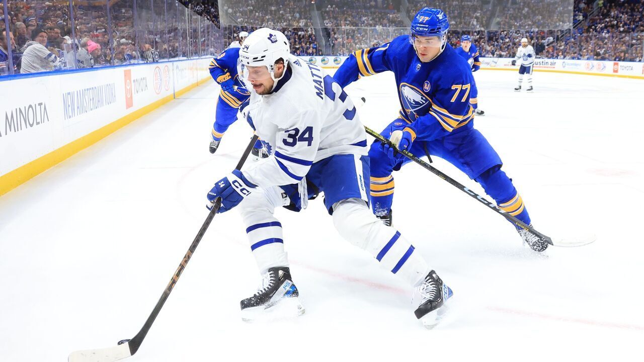 BUFFALO, NEW YORK - DECEMBER 21: Auston Matthews #34 of the Toronto Maple Leafs controls the puck against JJ Peterka #77 of the Buffalo Sabres during an NHL game on December 21, 2023 at KeyBank Center in Buffalo, New York.