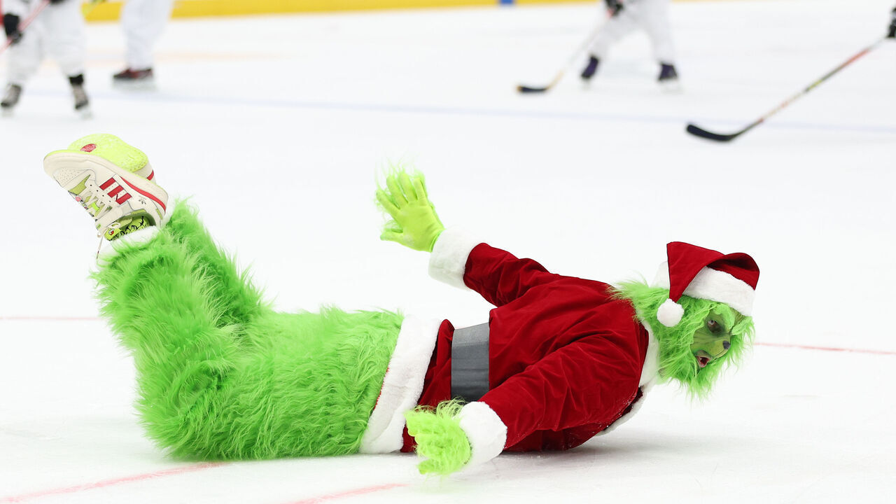 WASHINGTON, DC - DECEMBER 20: The Grinch slides on the ice as children play hockey during an intermission of an NHL game at Capital One Arena on December 20, 2023 in Washington, DC.