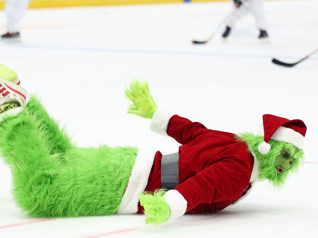 WASHINGTON, DC - DECEMBER 20: The Grinch slides on the ice as children play hockey during an intermission of an NHL game at Capital One Arena on December 20, 2023 in Washington, DC.