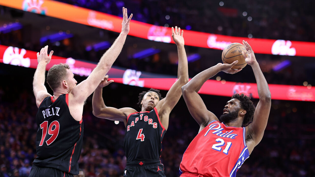 PHILADELPHIA, PENNSYLVANIA - DECEMBER 22: Joel Embiid #21 of the Philadelphia 76ers shoots over Jakob Poeltl #19 and Scottie Barnes #4 of the Toronto Raptors during the third quarter at the Wells Fargo Center on December 22, 2023 in Philadelphia, Pennsylvania.