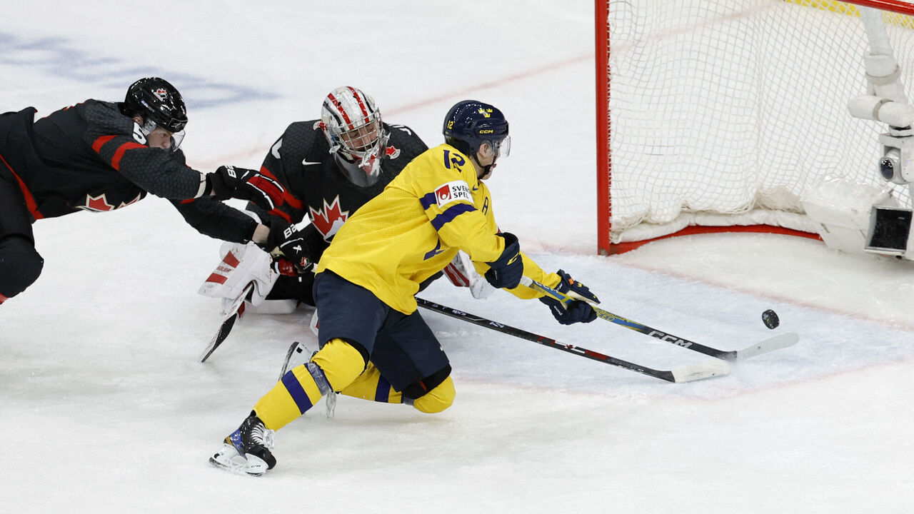 Canada's defender Oliver Bonk (L) and Canada's goalkeeper Mathis Rousseau (C) fail to stop Sweden's Noah Ostlund scoring the 0-2 goal during the Group A ice hockey match between Canada and Sweden of the IIHF World Junior Championship in Gothenburg, Sweden on December 29, 2023.