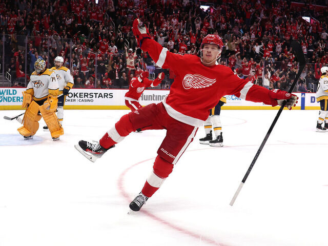 DETROIT, MICHIGAN - DECEMBER 29: Lucas Raymond #23 of the Detroit Red Wings celebrates his game winning goal in overtime in front of Juuse Saros #74 of the Nashville Predators at Little Caesars Arena on December 29, 2023 in Detroit, Michigan.