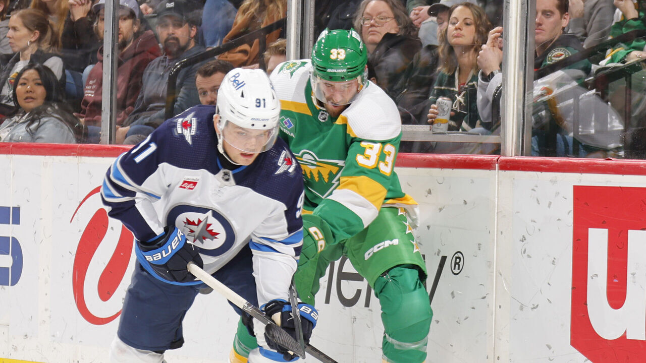 SAINT PAUL, MN - DECEMBER 31: Cole Perfetti #91 of the Winnipeg Jets skates with the puck while Alex Goligoski #33 of the Minnesota Wild defends during the game at the Xcel Energy Center on December 31, 2023 in Saint Paul, Minnesota.