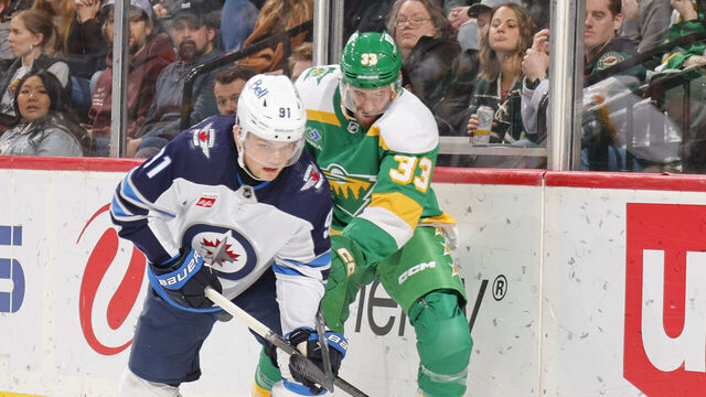 SAINT PAUL, MN - DECEMBER 31: Cole Perfetti #91 of the Winnipeg Jets skates with the puck while Alex Goligoski #33 of the Minnesota Wild defends during the game at the Xcel Energy Center on December 31, 2023 in Saint Paul, Minnesota.