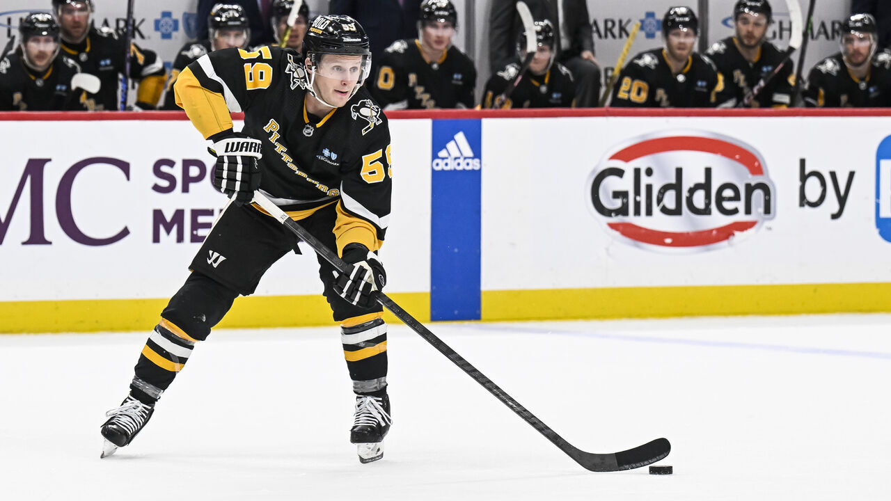 PITTSBURGH, PA - DECEMBER 21: Pittsburgh Penguins left wing Jake Guentzel (59) passes the puck during the overtime period in the NHL game between the Pittsburgh Penguins and the Carolina Hurricanes on December 21, 2023, at PPG Paints Arena in Pittsburgh, PA.