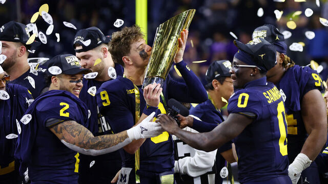 HOUSTON, TEXAS - JANUARY 08: J.J. McCarthy #9 of the Michigan Wolverines kisses the national championship trophy after defeating the Washington Huskies during the 2024 CFP National Championship game at NRG Stadium on January 08, 2024 in Houston, Texas. Michigan defeated Washington 34-13.