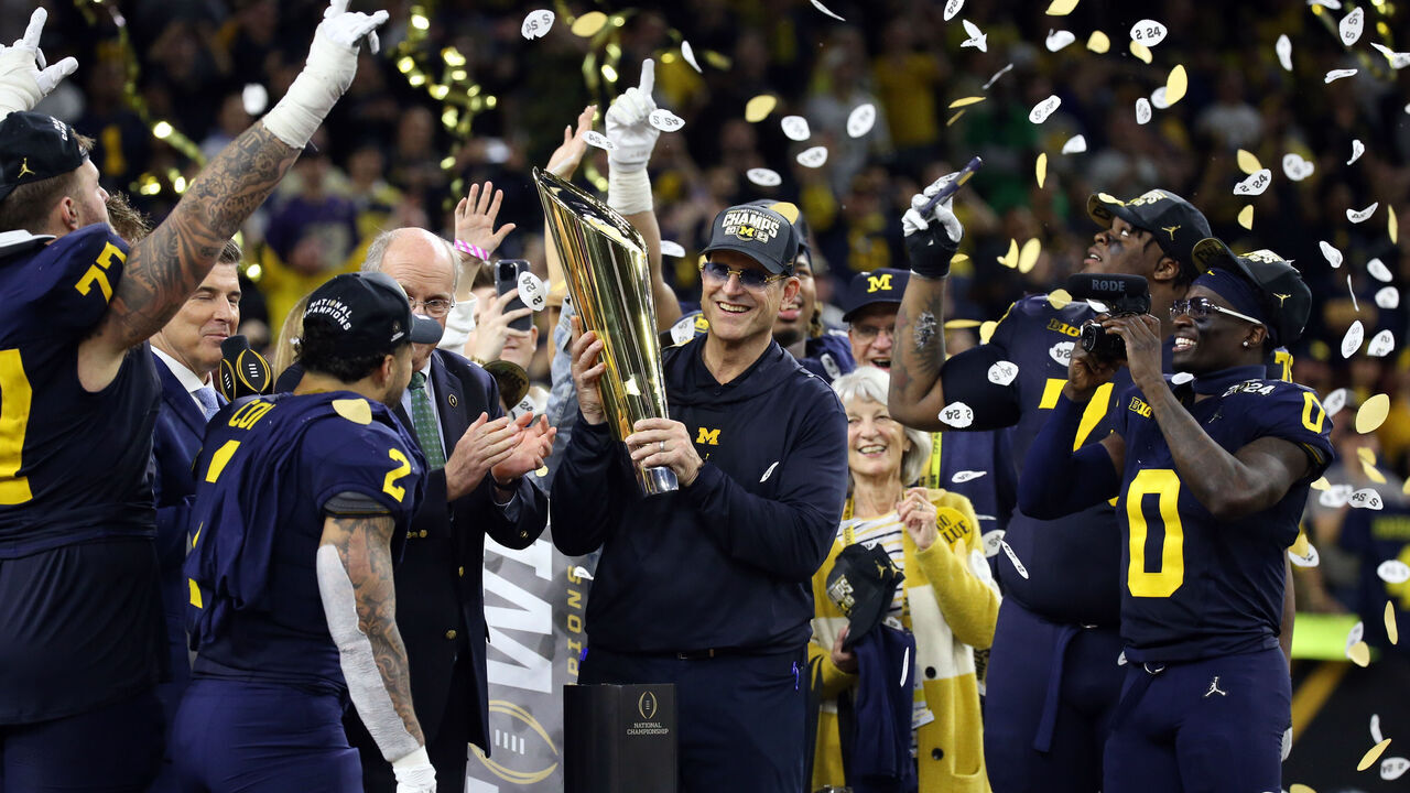 HOUSTON, TX - JANUARY 08: Head Coach Jim Harbaugh of the Michigan Wolverines lifts the National Championship trophy during the Michigan Wolverines versus the Washington Huskies CFP National Championship game on January 8, 2024, at NRG Stadium in Houston, TX.