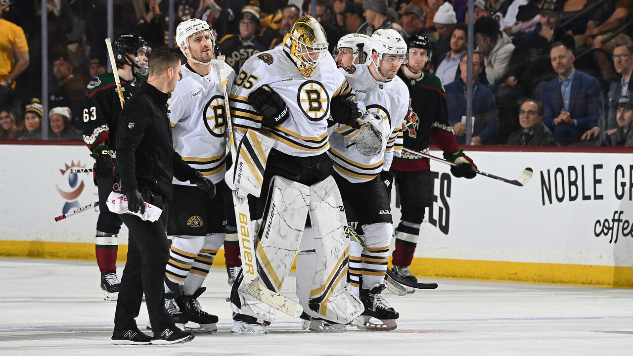 TEMPE, ARIZONA - JANUARY 09: Linus Ullmark #35 of the Boston Bruins is helped off the ice by teammates Kevin Shattenkirk #12 and Jake DeBrusk #74 during overtime against the Arizona Coyotes at Mullett Arena on January 09, 2024 in Tempe, Arizona.