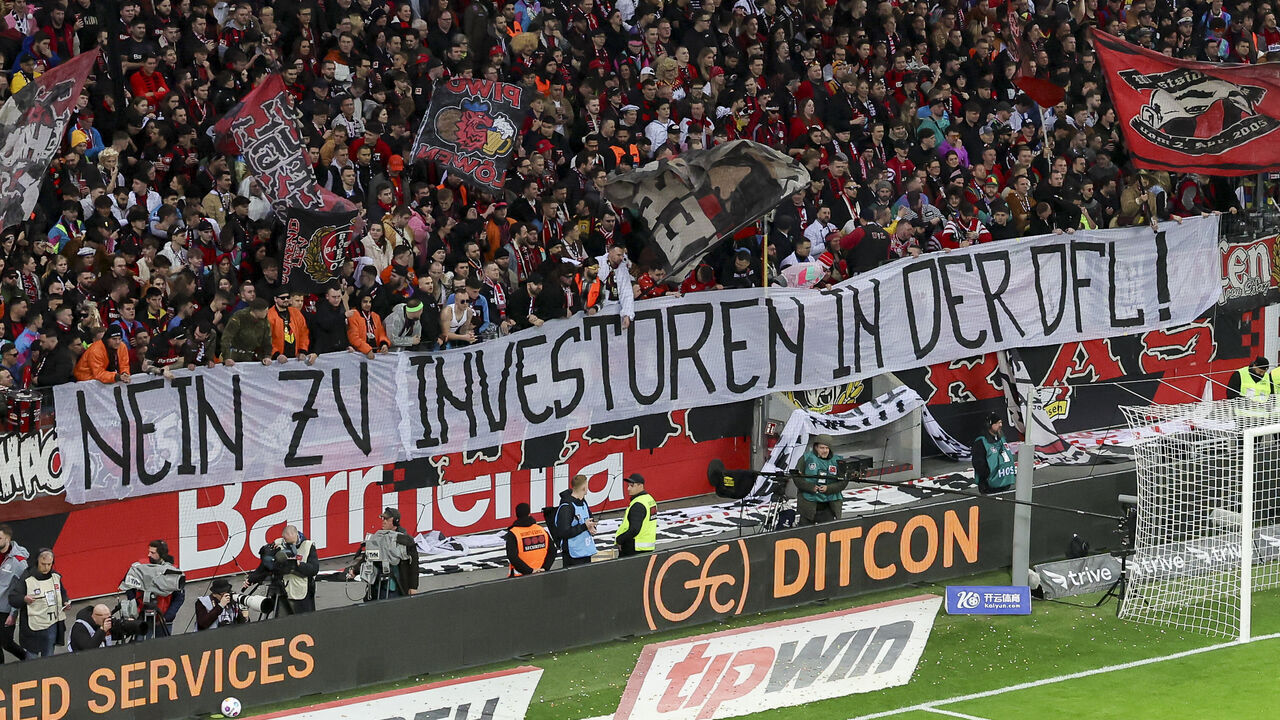 LEVERKUSEN, GERMANY - FEBRUARY 10: Leverkusen fans protest with a poster against the entry of investors into the German Football League during the Bundesliga match between Bayer 04 Leverkusen and FC Bayern München at BayArena on February 10, 2024 in Leverkusen, Germany.