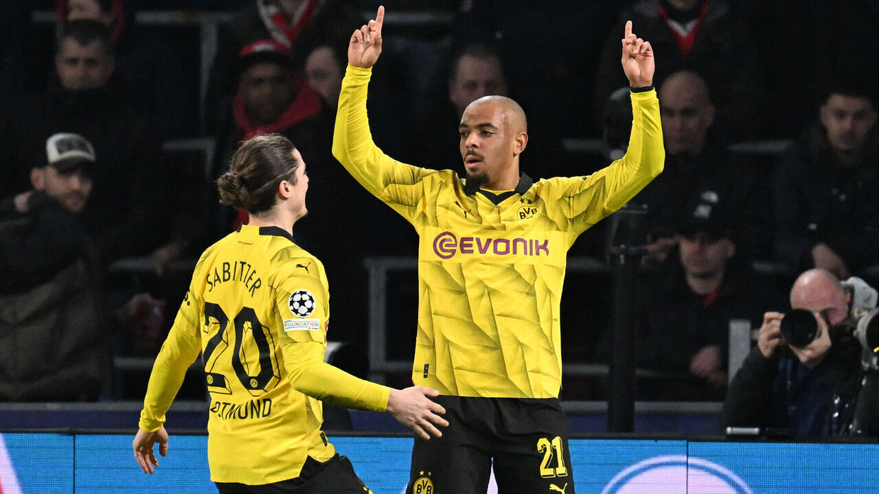 Dortmund's Dutch forward #21 Donyell Malen (R) celebrates scoring the first goal of the match during the UEFA Champions League round of 16, first leg football match between against PSV Eindhoven and Borussia Dortmund at the The Philips Stadium, in Eindhoven on February 20, 2024.