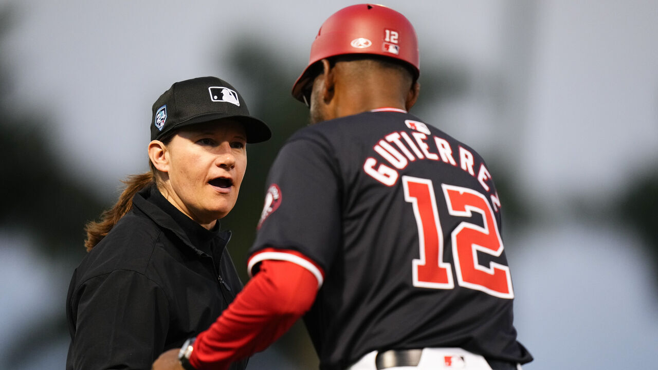 WEST PALM BEACH, FLORIDA - FEBRUARY 24: Umpire Jen Pawol shakes the hand of Washington Nationals third base coach Ricky Guiterrez #12 duringa spring training game against the Houston Astros at CACTI Park of the Palm Beaches on February 24, 2024 in West Palm Beach, Florida.