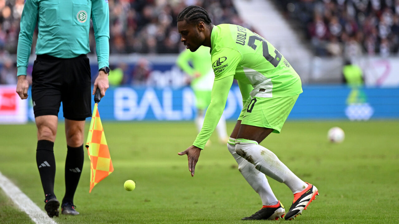 FRANKFURT AM MAIN, GERMANY - FEBRUARY 25: Ridle Baku of VfL Wolfsburg removes a tennis ball from the pitch after it was thrown in protest again the investment in the German league during the Bundesliga match between Eintracht Frankfurt and VfL Wolfsburg at Deutsche Bank Park on February 25, 2024 in Frankfurt am Main, Germany.
