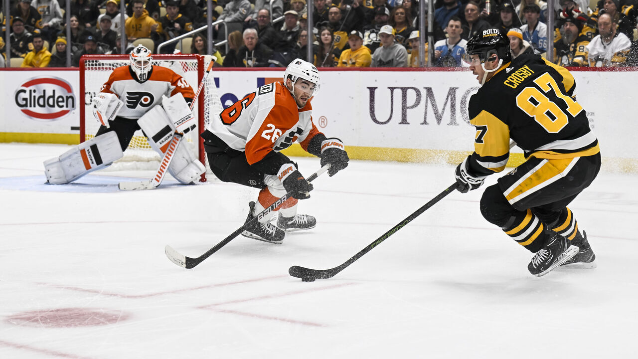 PITTSBURGH, PA - FEBRUARY 25: Pittsburgh Penguins center Sidney Crosby (87) stickhandes with the puck against Philadelphia Flyers defenseman Sean Walker (26) as Philadelphia Flyers goaltender Cal Petersen (40) tends net during the third period in the NHL game between the Pittsburgh Penguins and the Philadelphia Flyers on February 25, 2024, at PPG Paints Arena in Pittsburgh, PA.