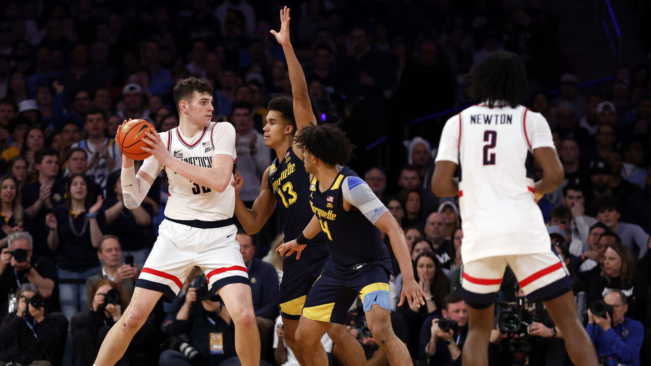 NEW YORK, NEW YORK - MARCH 16: Donovan Clingan #32 of the Connecticut Huskies dribbles as Oso Ighodaro #13 and Stevie Mitchell #4 of the Marquette Golden Eagles defend in the first half during the Big East Basketball Tournament Final at Madison Square Garden on March 16, 2024 in New York City.