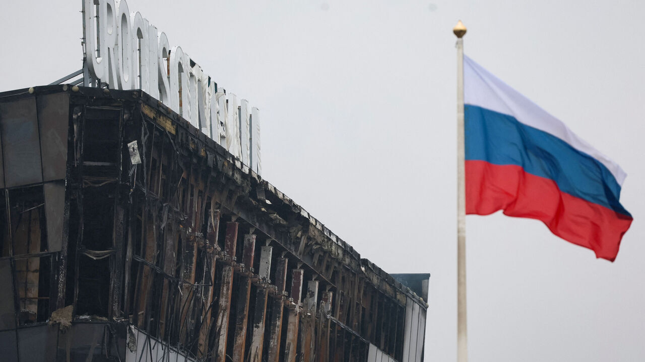 TOPSHOT - A Russian national tricolor flag flutters in the wind near the burned Crocus City Hall concert hall, the scene of the gun attack, in Krasnogorsk, outside Moscow, on March 23, 2024. Gunmen who opened fire at a Moscow concert hall killed more than 60 people and wounded over 100 while sparking an inferno, authorities said on March 23, 2024, with the Islamic State group claiming responsibility.