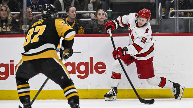 PITTSBURGH, PA - MARCH 26: Carolina Hurricanes left wing Jake Guentzel (59) shoots the puck against Pittsburgh Penguins center Sidney Crosby (87) during the third period in the NHL game between the Pittsburgh Penguins and the Carolina Hurricanes on March 26, 2024, at PPG Paints Arena in Pittsburgh, PA.