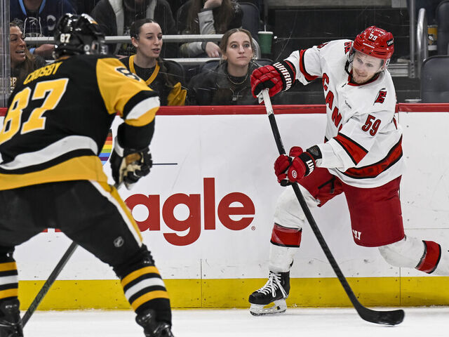 PITTSBURGH, PA - MARCH 26: Carolina Hurricanes left wing Jake Guentzel (59) shoots the puck against Pittsburgh Penguins center Sidney Crosby (87) during the third period in the NHL game between the Pittsburgh Penguins and the Carolina Hurricanes on March 26, 2024, at PPG Paints Arena in Pittsburgh, PA.