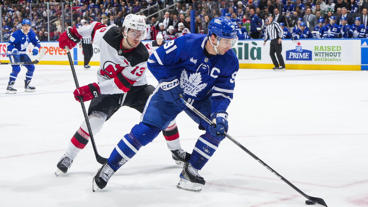 TORONTO, ON - MARCH 26: John Tavares #91 of the Toronto Maple Leafs plays the puck against Nico Hischier #13 of the New Jersey Devils during the second period at Scotiabank Arena on March 26, 2024 in Toronto, Ontario, Canada.