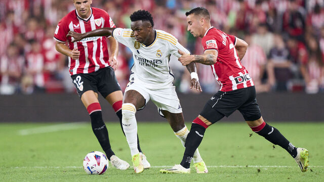 BILBAO, SPAIN - AUGUST 12: Vinicius Junior of Real Madrid duels for the ball with Gorka Guruzeta and Alex Berenguer of Athletic Club during the LaLiga EA Sports match between Athletic Club and Real Madrid CF at Estadio de San Mames on August 12, 2023 in Bilbao, Spain.