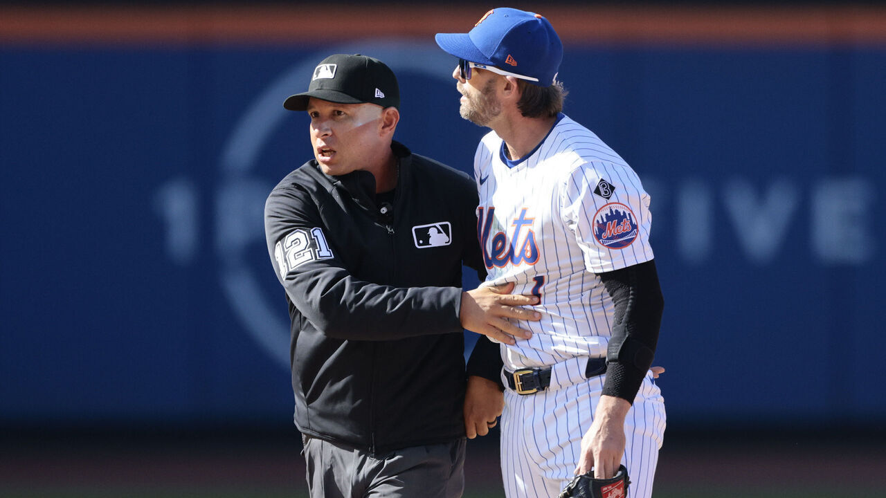 NEW YORK, NEW YORK - MARCH 29: Jeff McNeil #1 of the New York Mets is held back by umpire Jonathan Parra #121 after a play involving Rhys Hoskins #12 of the Milwaukee Brewers during the top of the eighth inning in the home opener at Citi Field on March 29, 2024 in New York City.