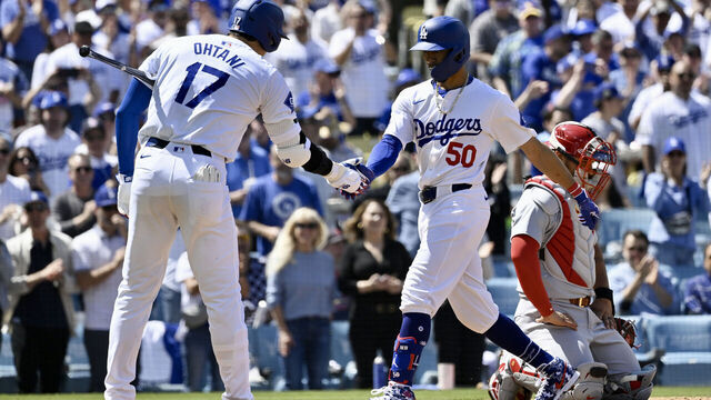 Los Angeles, CA - March 28: Mookie Betts #50 of the Los Angeles Dodgers high fives teammate Shohei Ohtani #17 after hitting a solo home run against the St. Louis Cardinals in the third inning of a opening day baseball game at Dodger Stadium in Los Angeles on Thursday, March 28, 2024.