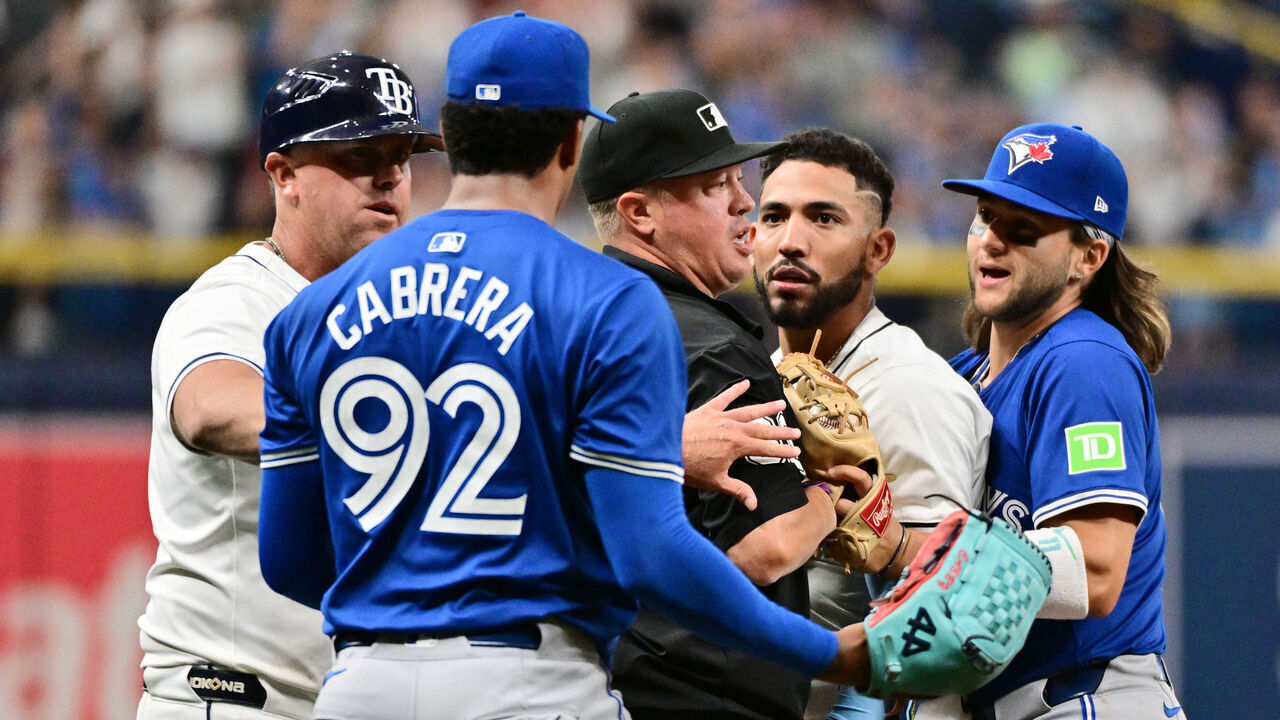 ST PETERSBURG, FLORIDA - MARCH 30: Umpire Cory Blaser #89 (C) stands between Jose Caballero #7 of the Tampa Bay Rays and Genesis Cabrera #92 of the Toronto Blue Jays after a dugout clearing shove in the seventh inning at Tropicana Field on March 30, 2024 in St Petersburg, Florida.