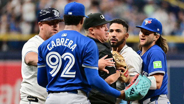 ST PETERSBURG, FLORIDA - MARCH 30: Umpire Cory Blaser #89 (C) stands between Jose Caballero #7 of the Tampa Bay Rays and Genesis Cabrera #92 of the Toronto Blue Jays after a dugout clearing shove in the seventh inning at Tropicana Field on March 30, 2024 in St Petersburg, Florida.