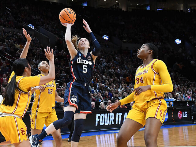 PORTLAND, OR - APRIL 01: UConn Huskies guard Paige Bueckers (5) shoots over USC Trojans guard Kayla Padilla (45) and USC Trojans center Clarice Akunwafo (34) during a 2024 Div I Women's Basketball Championship Elite Eight game between the UConn Huskies and USC Trojans on April 1, 2024 at Moda Center in Portland, Oregon.