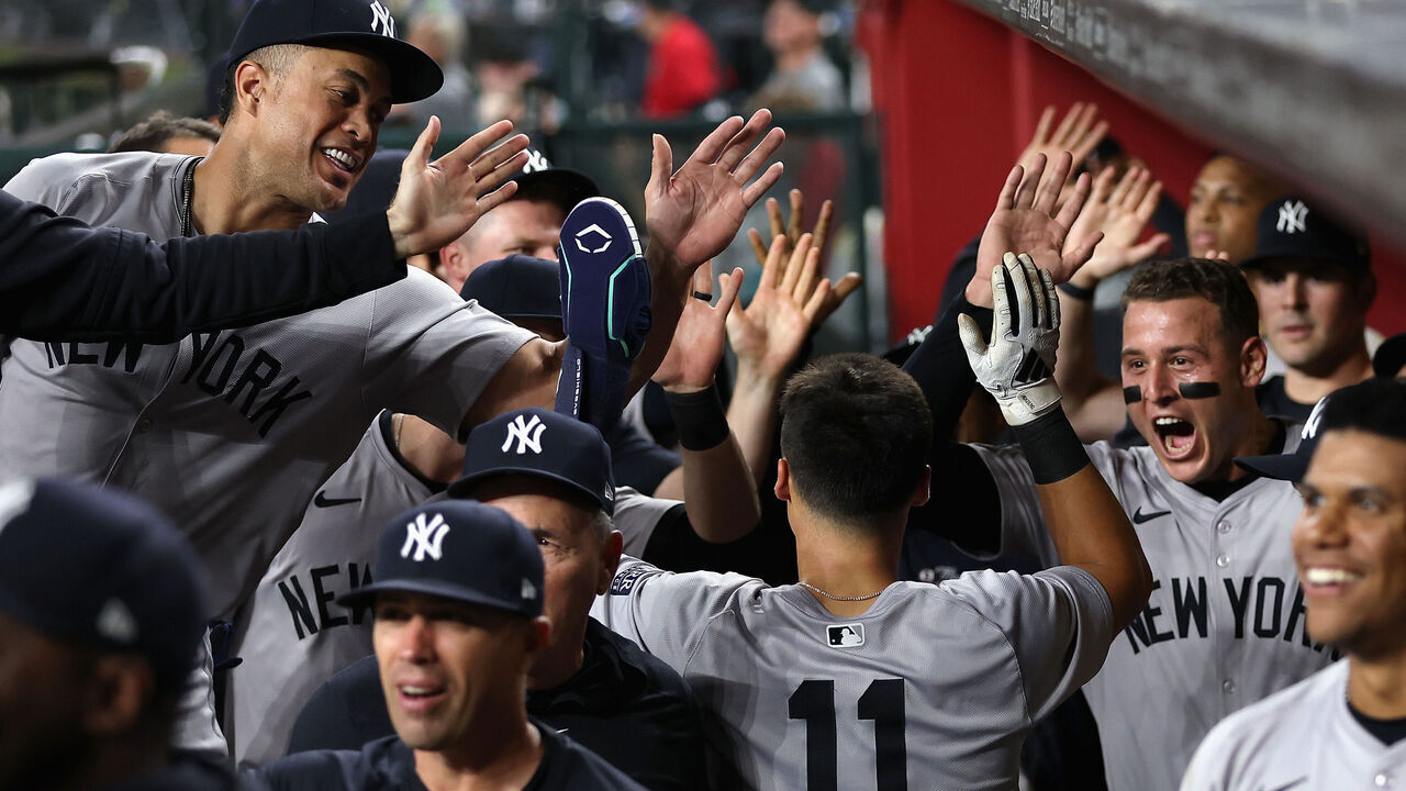 PHOENIX, ARIZONA - APRIL 01: Anthony Volpe #11 of the New York Yankees high fives Anthony Rizzo #48 and Giancarlo Stanton #27 in the dugout after scoring a run against the Arizona Diamondbacks during the third inning of the MLB game at Chase Field on April 01, 2024 in Phoenix, Arizona.