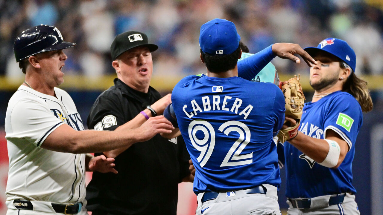 ST PETERSBURG, FLORIDA - MARCH 30: Genesis Cabrera #92 of the Toronto Blue Jays shoves Jose Caballero #7 of the Tampa Bay Rays as third base coach Brady Williams #4 (L), umpire Corey Blaser (2nd-L), and Bo Bichette #11 (R) attempt to intervene in the seventh inning at Tropicana Field on March 30, 2024 in St Petersburg, Florida.