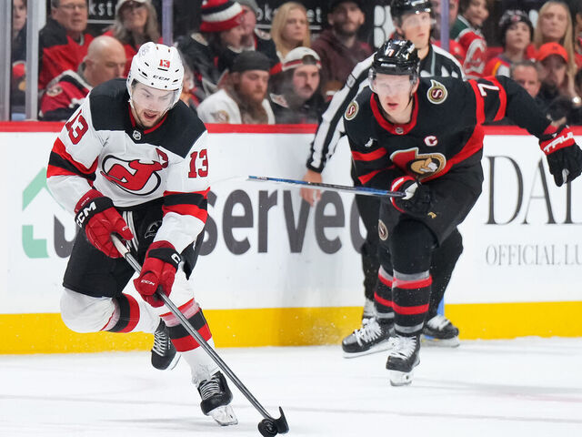 OTTAWA, CANADA - DECEMBER 29: Nico Hischier #13 of the New Jersey Devils skates up ice with the puck against Brady Tkachuk #7 of the Ottawa Senators at Canadian Tire Centre on December 29, 2023 in Ottawa, Ontario, Canada.