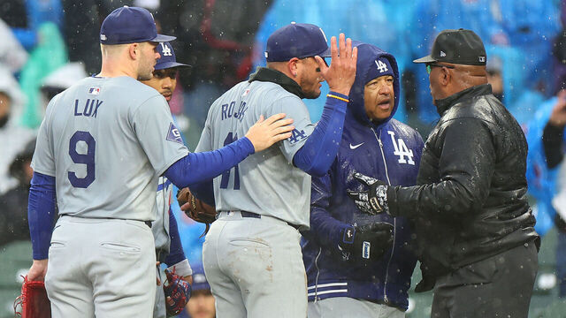CHICAGO, ILLINOIS - APRIL 07: Manager Dave Roberts #30 and Miguel Rojas #11 of the Los Angeles Dodgers argues with umpire Laz Diaz #63 after the game was delayed during the fourth inning against the Chicago Cubs at Wrigley Field on April 07, 2024 in Chicago, Illinois.
