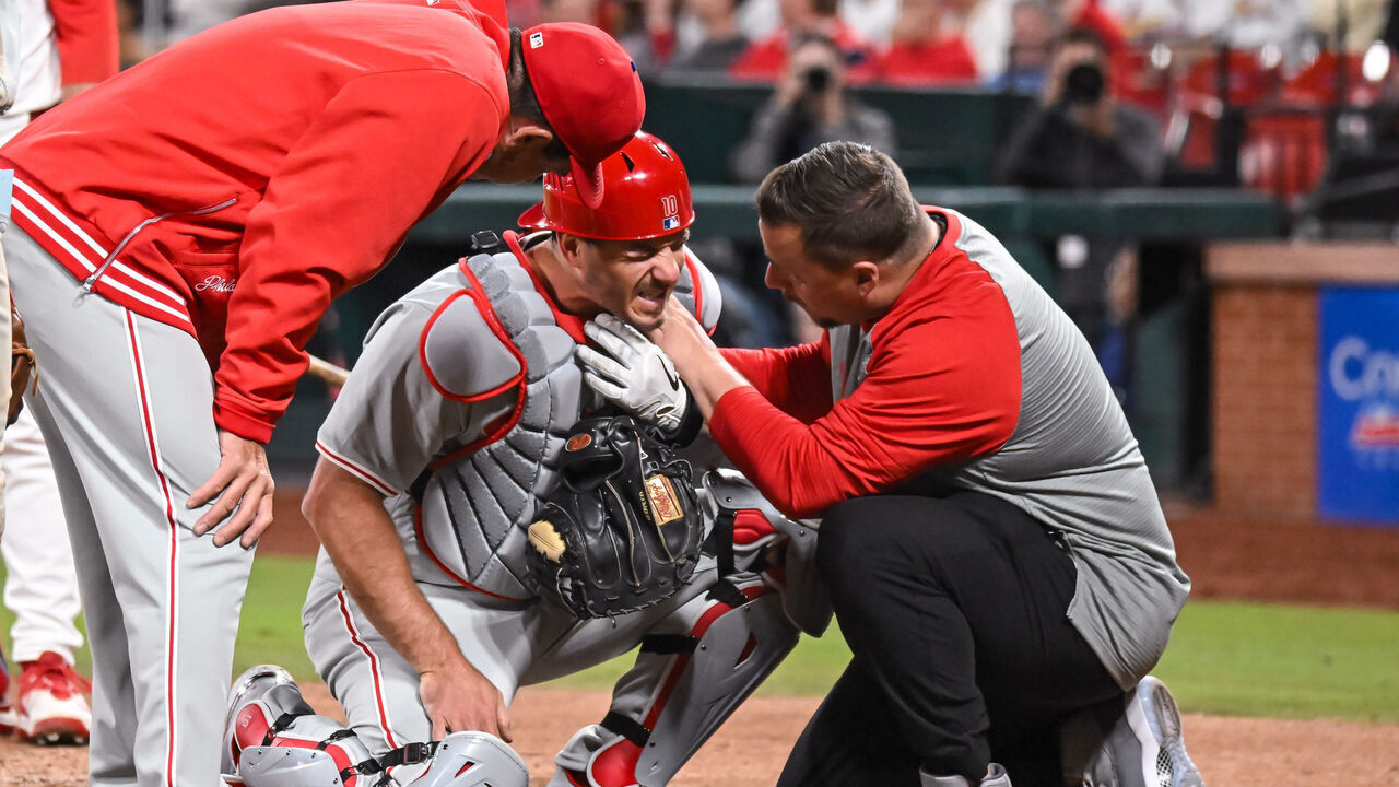 ST. LOUIS, MO - Apr 9: Philadelphia Phillies catcher J.T. Realmuto (10) has his collar bone checked by the team trainer while Philadelphia Phillies manager Rob Thomson (59) checks in on him during a game between the Philadelphia Phillies and the St. Louis Cardinals on Tuesday April 9, 2024, at Busch Stadium in St. Louis MO