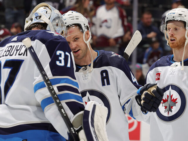 DENVER, COLORADO - APRIL 13: Goaltender Connor Hellebuyck #37, Josh Morrissey #44 and Kyle Connor #81 of the Winnipeg Jets celebrate a 7-0 win against the Colorado Avalanche at Ball Arena on April 13, 2024 in Denver, Colorado.
