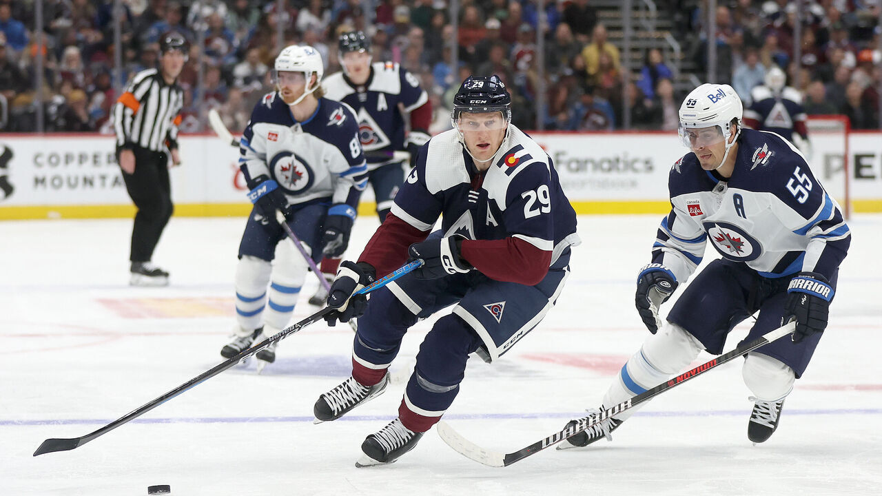DENVER, COLORADO - DECEMBER 07: Nathan MacKinnon #29 of the Colorado Avalanche advances the puck against Mark Scheifele #55 of the Winnipeg Jets in the second period at Ball Arena on December 07, 2023 in Denver, Colorado.