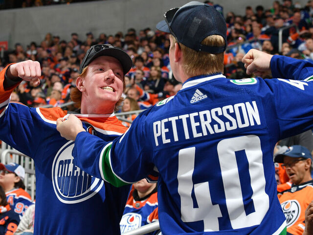 EDMONTON, CANADA - APRIL 13: An Edmonton Oilers fan and Vancouver Canucks fan pose for a photo at Rogers Place on April 13, 2024, in Edmonton, Alberta, Canada.