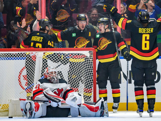 VANCOUVER, CANADA - DECEMBER 5: Nils Hoglander #21 is congratulated by J.T. Miller #9 Quinn Hughes #43 and Brock Boeser #6 of the Vancouver Canucks after scoring a goal on Vitek Vanecek #41 of the New Jersey Devils during the third period of their NHL game at Rogers Arena on December 5, 2023 in Vancouver, British Columbia, Canada.