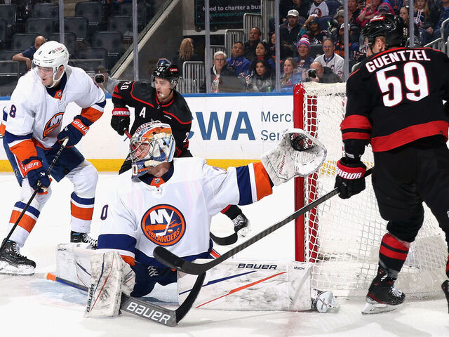 ELMONT, NEW YORK - MARCH 19: The New York Islanders defend against Sebastian Aho #20 and Jake Guentzel #59 of the Carolina Hurricanes during the first period at UBS Arena on March 19, 2024 in Elmont, New York.