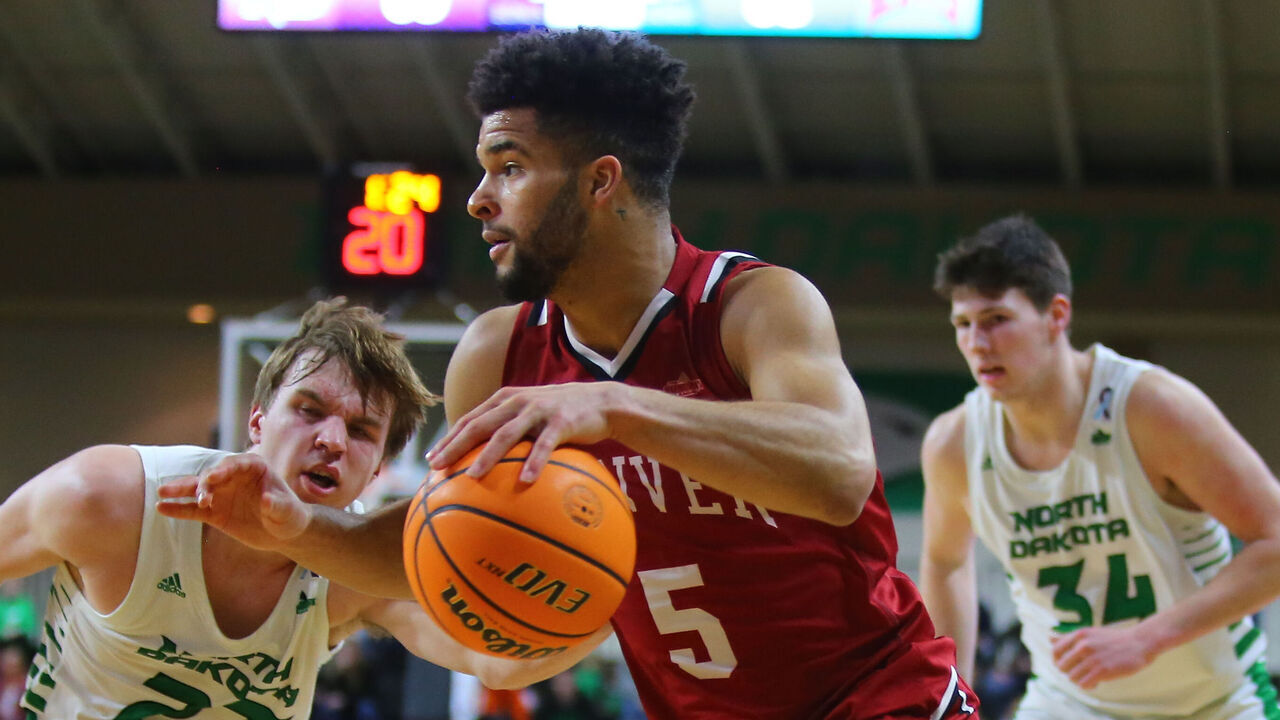 GRAND FORKS, ND - FEBRUARY 03: Denver Pioneers guard Coban Porter (5) drives to the basket guarded by North Dakota Fighting Hawks guard Paul Bruns (23) and North Dakota Fighting Hawks forward Brian Mathews (34) during the Summit League mens basketball contest between the North Dakota Fighting Hawks and the Denver Pioneers on February 03, 2022, at the Betty Engelstad Sioux Center in Grand Forks, ND.