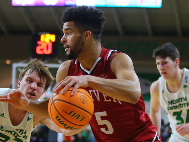 GRAND FORKS, ND - FEBRUARY 03: Denver Pioneers guard Coban Porter (5) drives to the basket guarded by North Dakota Fighting Hawks guard Paul Bruns (23) and North Dakota Fighting Hawks forward Brian Mathews (34) during the Summit League mens basketball contest between the North Dakota Fighting Hawks and the Denver Pioneers on February 03, 2022, at the Betty Engelstad Sioux Center in Grand Forks, ND.