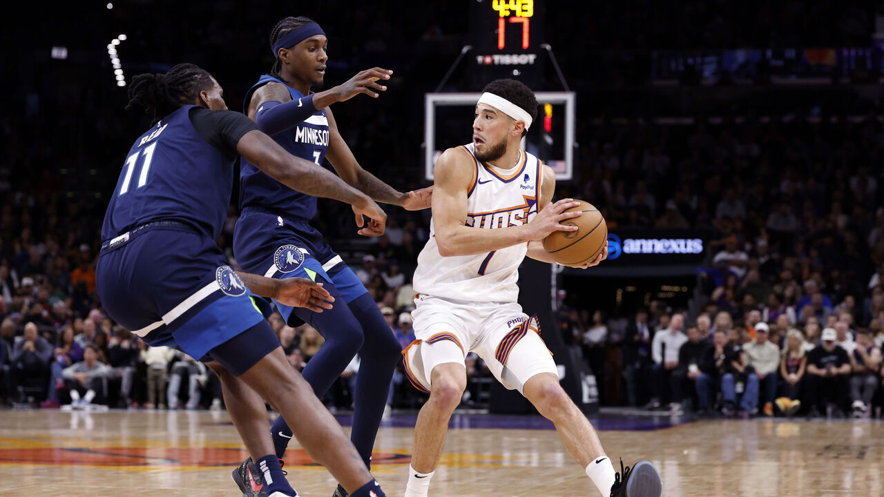 PHOENIX, ARIZONA - APRIL 05: Naz Reid #11 and Jaden McDaniels #3 of the Minnesota Timberwolves pressure Devin Booker #1 of the Phoenix Suns during the game at Footprint Center on April 05, 2024 in Phoenix, Arizona. The Suns defeated the Timberwolves 97-87.