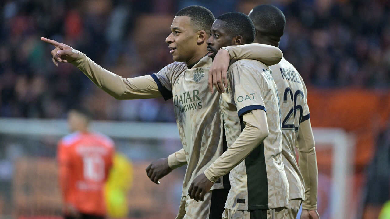 Paris Saint-Germain's French forward #07 Kylian Mbappe (L) embraces Paris Saint-Germain's French forward #10 Ousmane Dembele (C) as they celebrate their victory at the end of the French L1 football match between FC Lorient and Paris Saint-Germain (PSG) at the Stade du Moustoir in Lorient, western France, on April 24, 2024.
